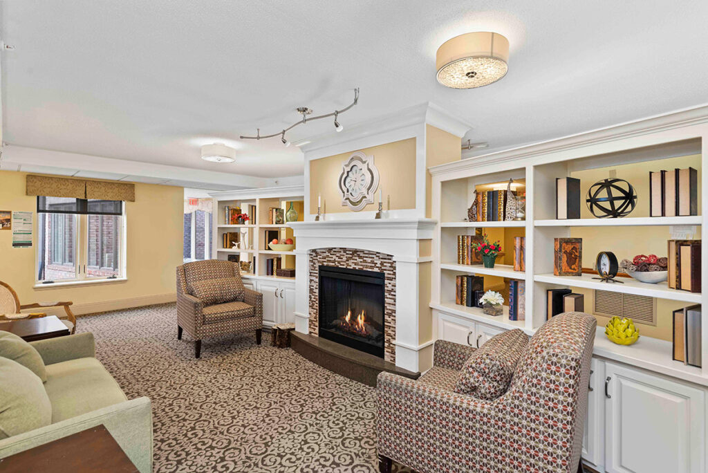 community area with sitting chairs, fireplace, bookshelves at Ephrata Manor